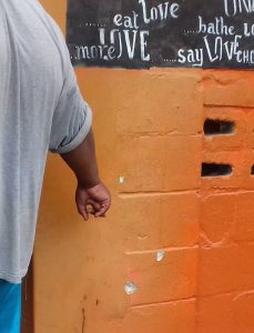 A witness points to bullet holes that were left behind when gunmen shot up a bar on a street off Sunshine Avenue, San Juan. the shooting resulted in the death of one man, and the wounding of three others. 