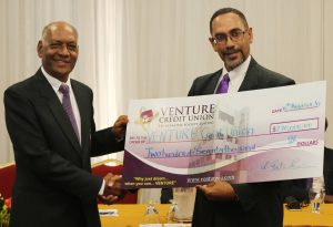 Lionel Sookoo (left), chairman of the 5k committee, collects a cheque valued at $270,000 from Roger Bertrand, president of Venture Credit Union, at yesterday's media conference.