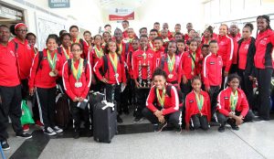 Members of Trinidad and Tobago’s Goodwill swim team pose with their medals and overall trophy at the Piarco International Airport yesterday.