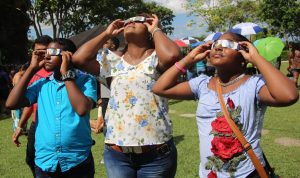 SUN-GAZING: The Jaichand family looks through their shades, which were provided by the TT Astro Club to look at the eclipse at from San Fernando Hill yesterday. At left is Vikash, his mother Sally Ann,centre, and sister Renushka Jaichand.