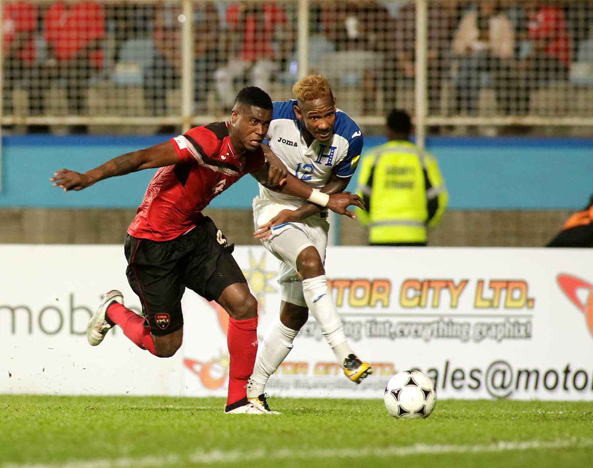 Trinidad and Tobago’s Sheldon Bateau, left, and Honduras’ Romell Quioto vie for the ball last Friday in a World Cup qualifier at the ATo Boldon Stadium, Couva.