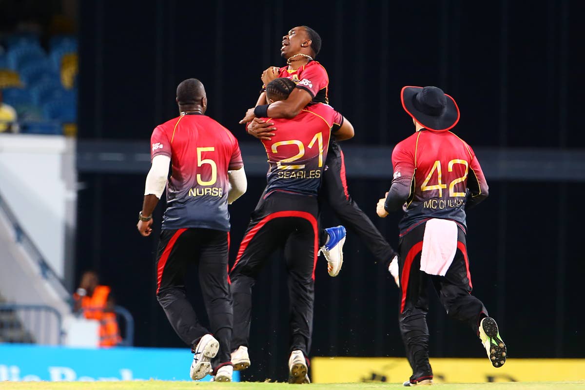 Trinbago Knight Riders captain Dwayne Bravo, centre, jumps to hug teammate Javon Searles after he took a wicket against the Barbados Tridents recently.