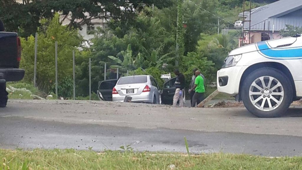 Police officers inspect the abandoned silver Nissan Tiida at Tank Road, Signal Hill which was said to be involved in a foiled robbery at Lambeau and a subsequent shootout with a police officer last Wednesday.