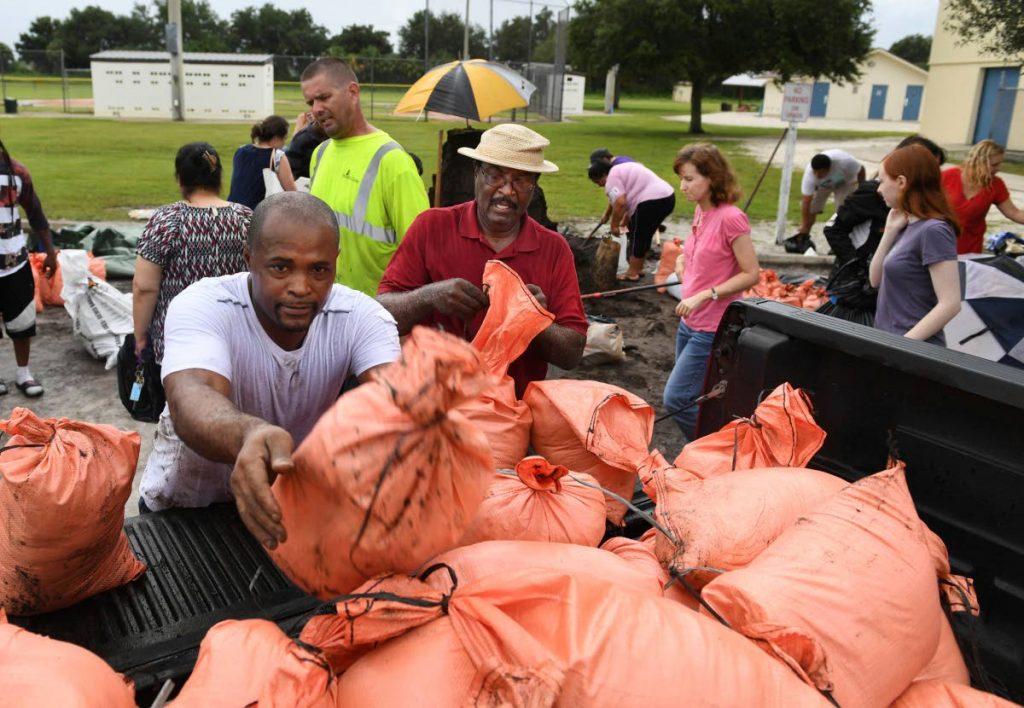 BAG ‘EM: James Byrd, left, and Richard Clark, right, load their sandbags in a truck yesterday, at Newtown Estates Recreation Centre in Sarasota, Fla., as they prepare for Hurricane Irma. They each got their ten bags before Sarasota County ran out of sandbags for residents. The county still has plenty of dirt but residents must bring and fill their own bags. A new shipment of sandbags is expected today. (via AP)