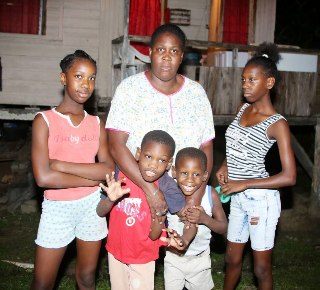 Natalie Warren, 42, center, with four of her five children (Jewel, Criston, Shakeen and Alyia) in front of a rented house in Morne Diablo. 