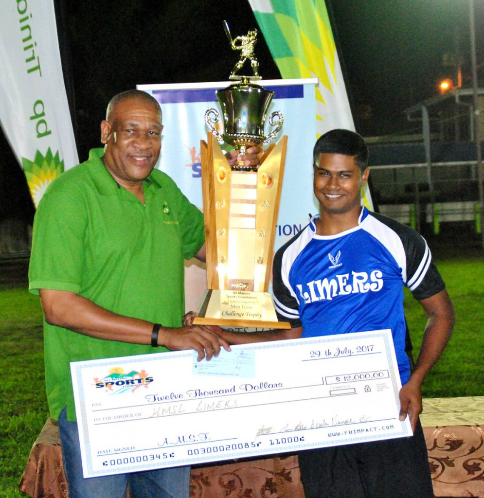 BPTT’s Matthew Pierre (left) presents the coveted league championship trophy and winners’ cheque to Mark Rampersad, captain of Limers, at the presentation of prizes in the 2017 BPTT Mayaro Night Windball Cricket League.