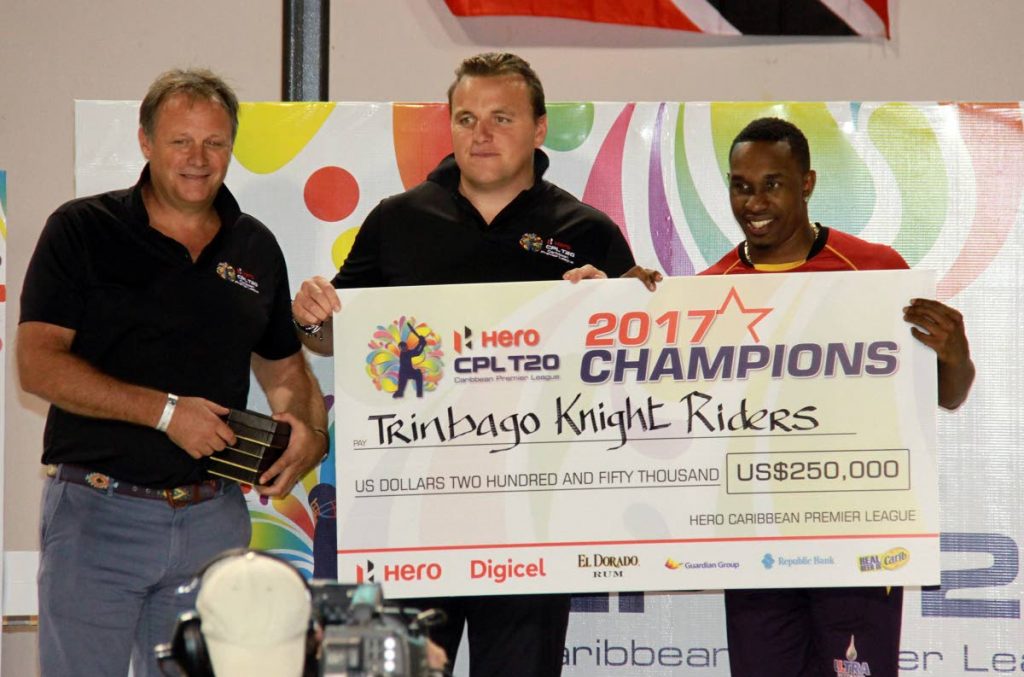 Dwayne Bravo, captain of the Trinbago Knight Riders, collect the US $250,000 cheque from CPL chief executive Damien O'Donohue (centre) while an unnamed CPL official looks on, during the presentation ceremony at the Brian Lara Cricket Academy, Tarouba. 