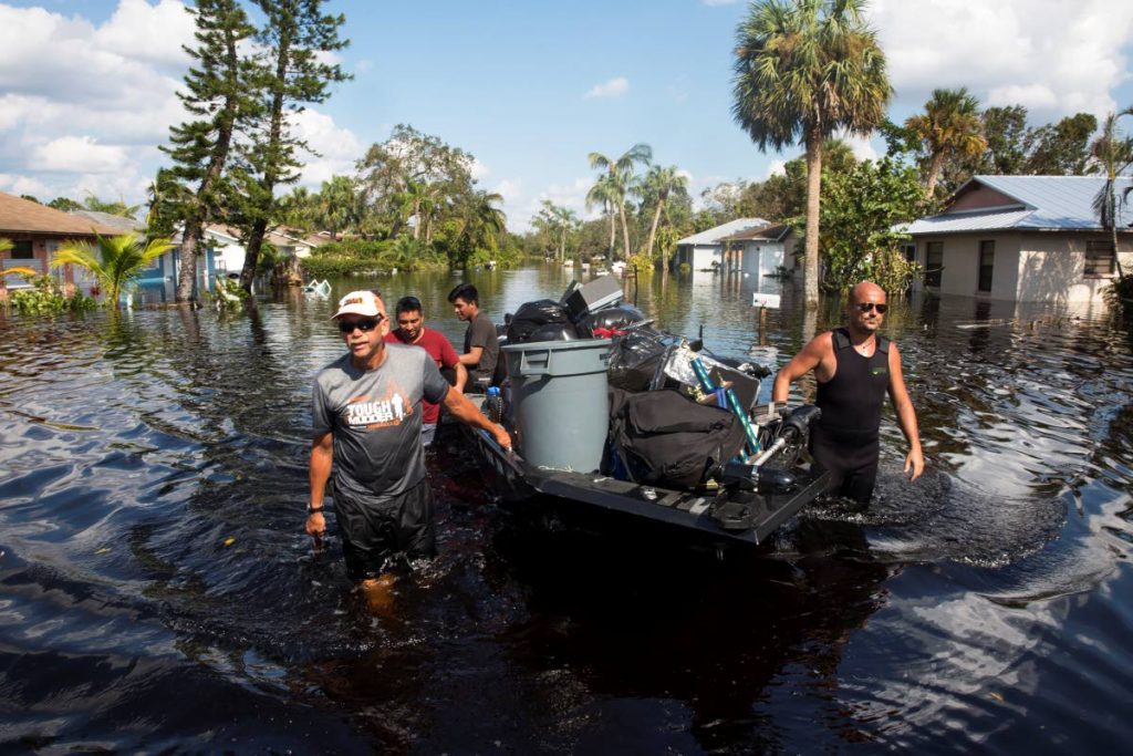 Still under water: Don Manley, left, and Pedro Castellano, right, pull Manley’s boat, loaded with residents’ belongings, along a flooded Chapman Avenue in Bonita Springs, Florida on September 15, almost a week after the passage of Hurricane Irma.