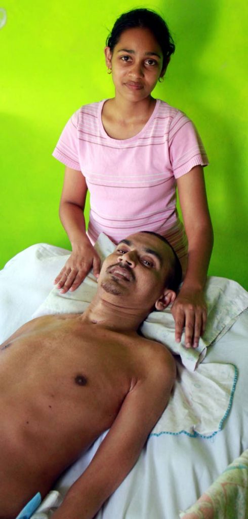 HELP US: Karen Ganesh with her bedridden 
husband Marcus at their HDC home in
 Longdenville. Marcus, who was shot twice in 2012 during a robbery, has been given an eviction 
notice from the HDC.
