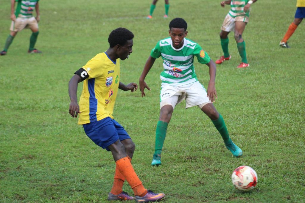 A Carapichaima player (left) tries to get past his St Augustine opponent during yesterday’s clash at St Augustine Ground.