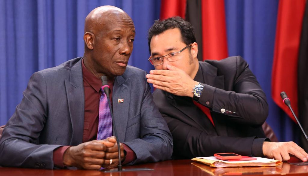 SHOO-SHOOING: Prime Minister Keith Rowley listens as Minister in the Office of the Prime Minister Stuart Young whispers to him yesterday at the post Cabinet press briefing at the Diplomatic Centre in St Ann’s.