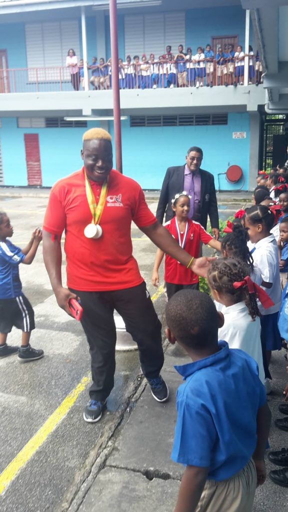 Paralympic gold medallist Akeen Stewart left, greets students at the Sangre Grande Government Primary School during a tour organised by the Sangre Grande Regional Corporation last year.