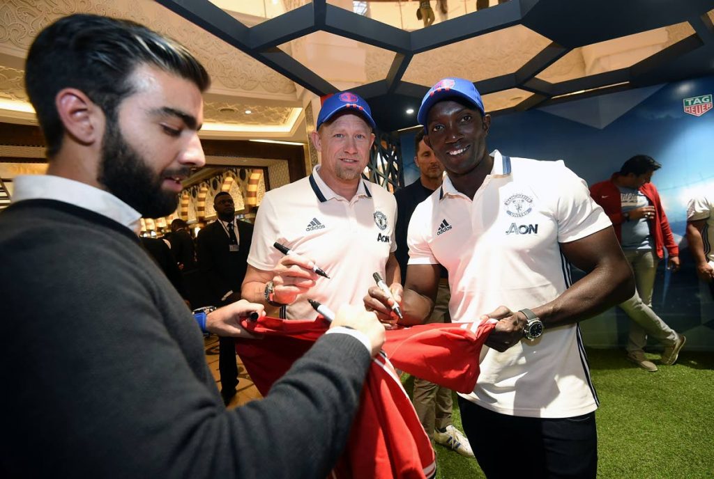 Dwight Yorke (right) and former Manchester United goalkeeper Peter Schmeichel (centre) delight a fan with autographs at a Dubai Mall Tag Heuer event recently.