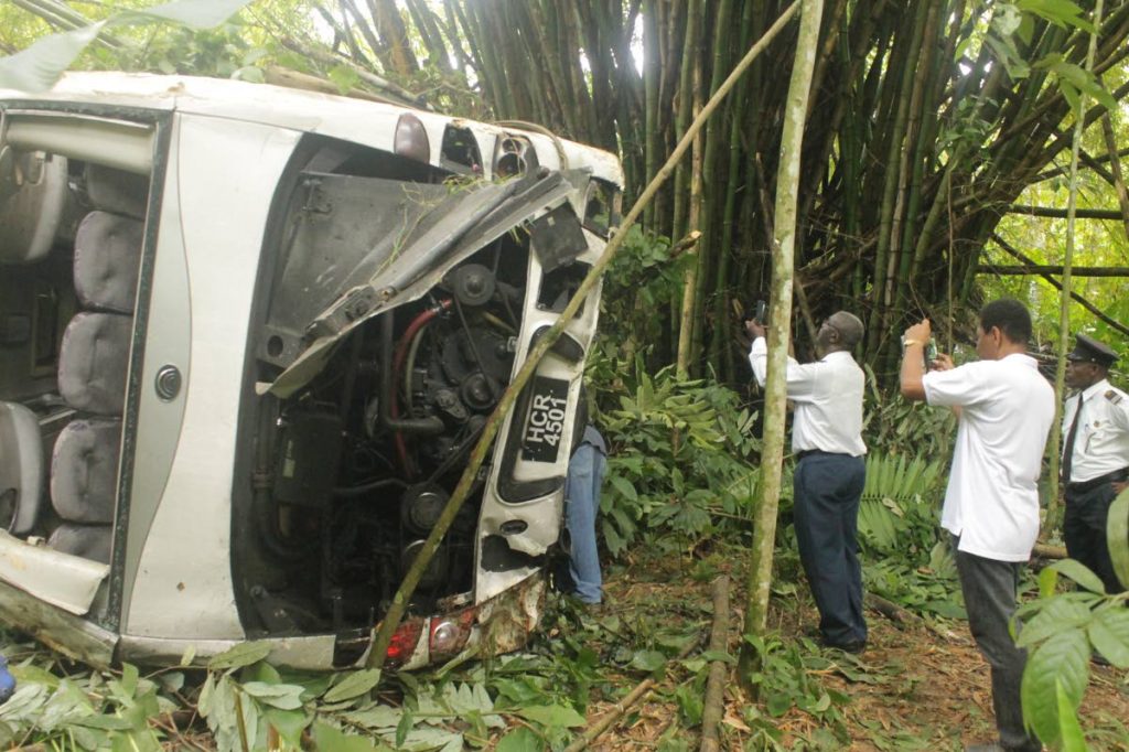 Henry Cooke, PTSC Area Manager, Tobago, and officers of the Tobago Division of the Licensing Office take photos of the destroyed bus which, along with the driver and five passengers, plunged down a precipice in LAnse Fourmi on October 10, 2016.