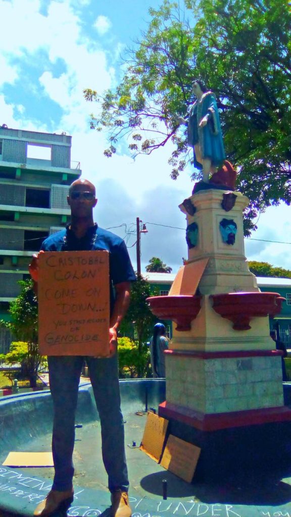 Shabaka Kambon, coordinator and founder of the Cross Rhodes Freedom project stands with a picket sign near Columbus statue in downtown Port-of-Spain yesterday. Kambon is calling for a removal of the statue and an end to a 'whitewashing' of history in T&T. PHOTO BY SHANE SUPERVILLE