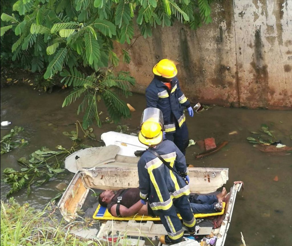 Firemen remove the body of a truck driver from the wreck of his vehicle in Chaguanas yesterday.