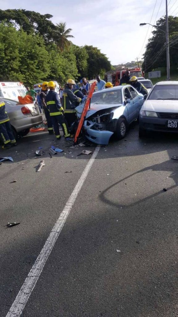 DEADLY CRASH: Firemen, near to the Signal Hill intersection, Tobago gain entry to a smashed Mitsubishi Lancer, which was driven by Mohammed Khan ,85, on Monday morning when he was involved in an accident which claimed his life.