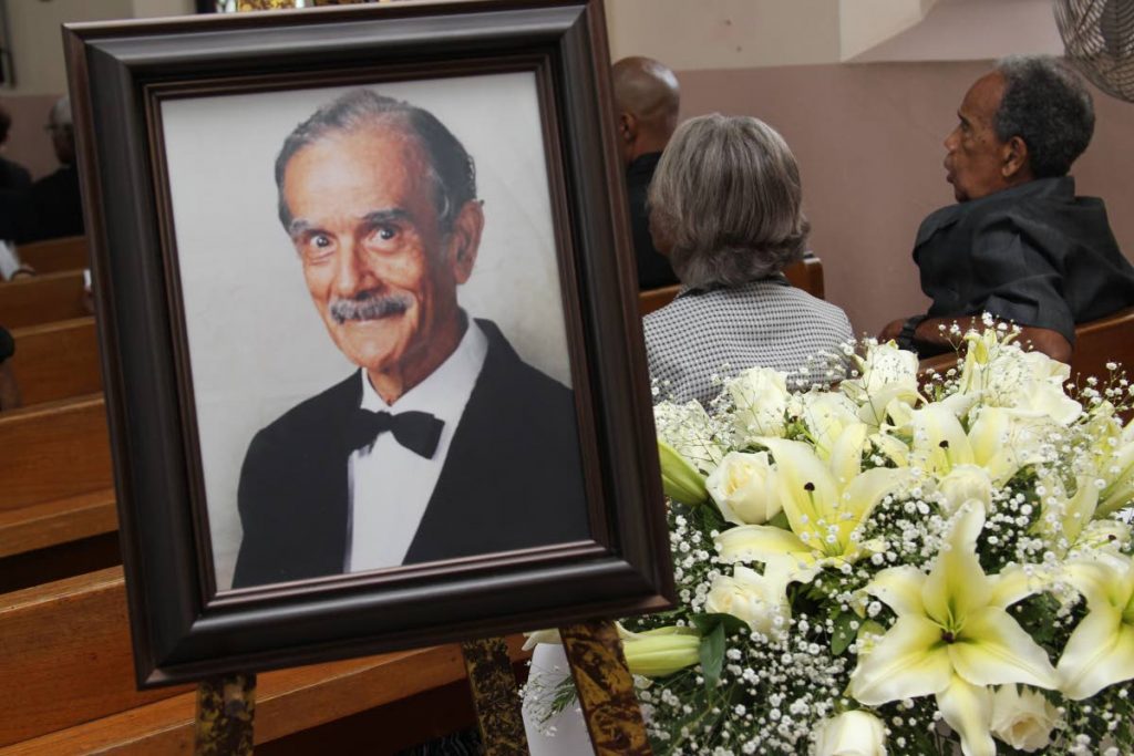In memorium: Mourners sit near a portrait of retired Chief Justice Cecil Kelsick at his funeral. PHOTO BY RATTAN JADOO