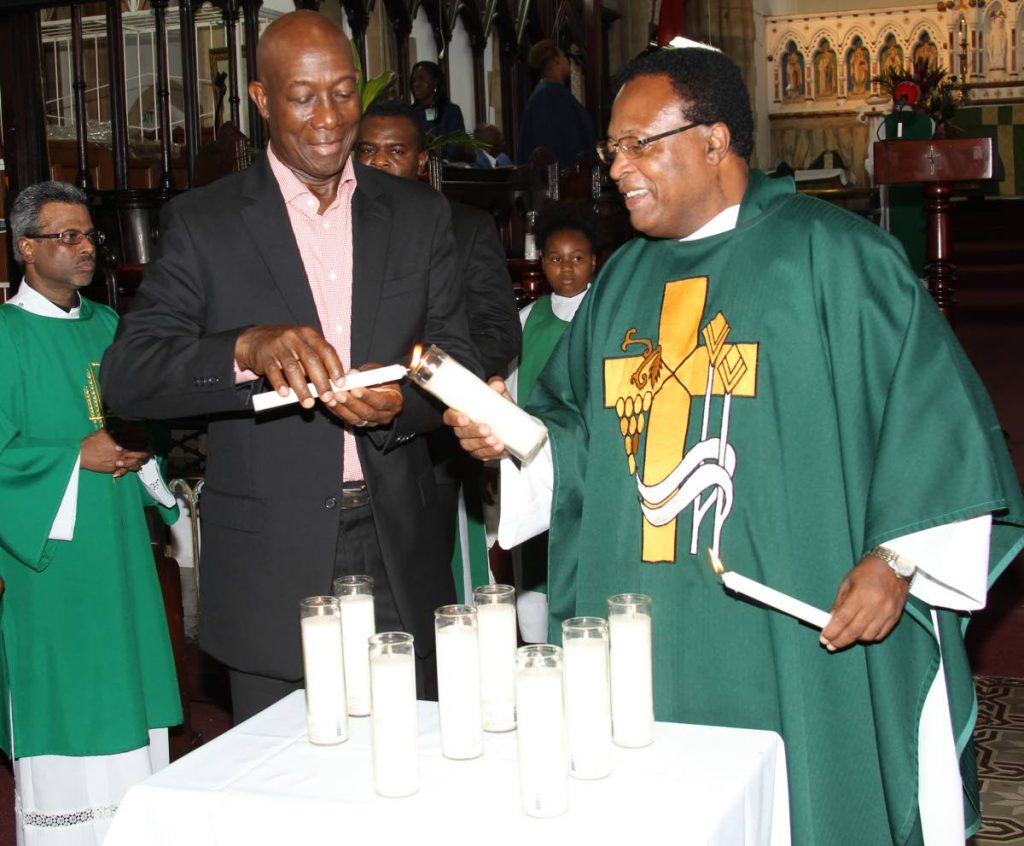 LIGHT IN REMEMBRANCE: Prime Minister Dr Keith Rowley and Rev Carl Williams light candles in remembrance of those who died in recent Caribbean hurricanes during a service yesterday at the Holy Trinity Cathedral in Port of Spain. PHOTO BY RATTAN JADOO. 