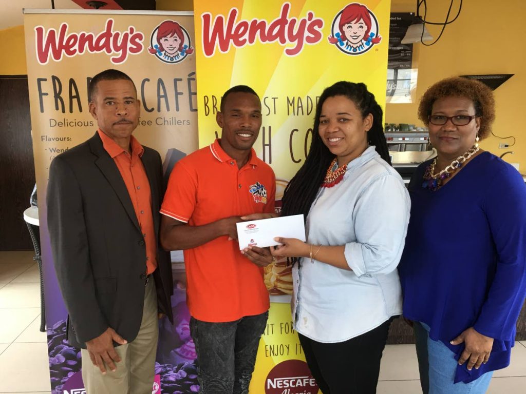 Club Sando midfielder Akim Armstrong (second from left), is presented with Wendy’s Pro League Player of the Month vouchers for July from Sheyna Weston, marketing manager at Desk Restaurants—the franchise holder of Wendy’s (Trinidad and Tobago), at Wendy’s Ariapita Avenue restaurant in Woodbrook on September 15. At left TT Pro League CEO Dexter Skeene and extreme right is Julia Baptiste, general secretary of the Pro League.