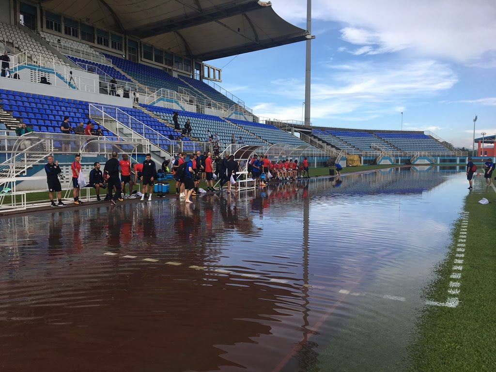 USA team officials and players contemplate whether to walk through the flooded track area to get to the field at the Ato Boldon Stadium in Couva this morning. PHOTO COURTESY US SOCCER