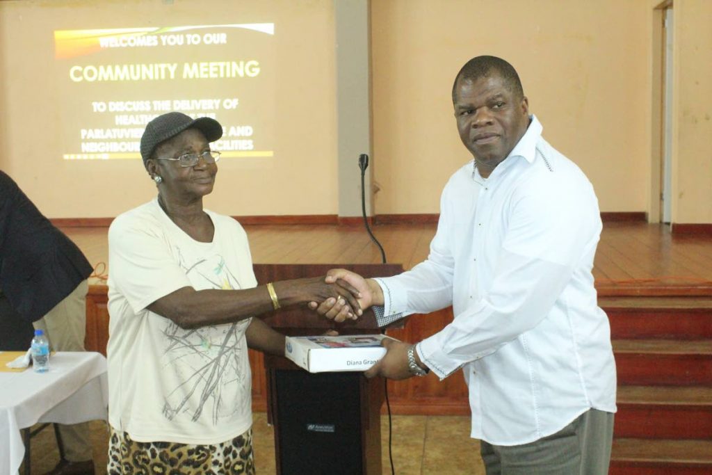  Carlos Waldron, Director of Finance, TRHA, presents a 211 Emergency Medical Alert System to Mary Plante, on behalf of her sister Diana Grant at a community meeting at the Parlatuvier community centre last Tuesday.