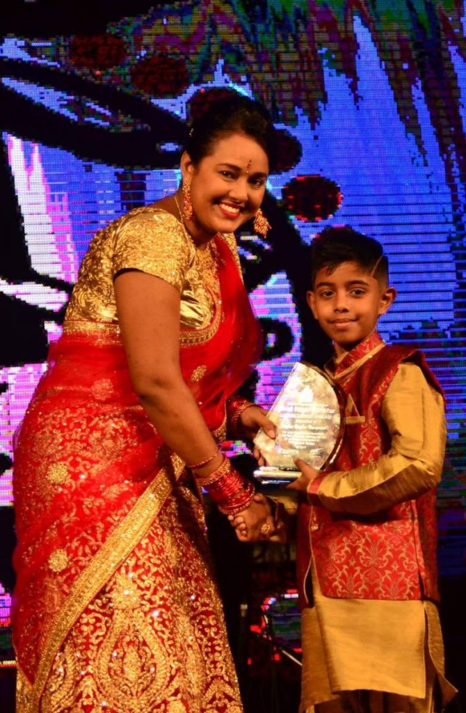 Rayden Rampersad, right, receives an award for his achievements in chess from Leanne Dianne Dookie, executive member of the NCIC and Miss NCIC Divali Nagar Queen Pageant Coordinator.