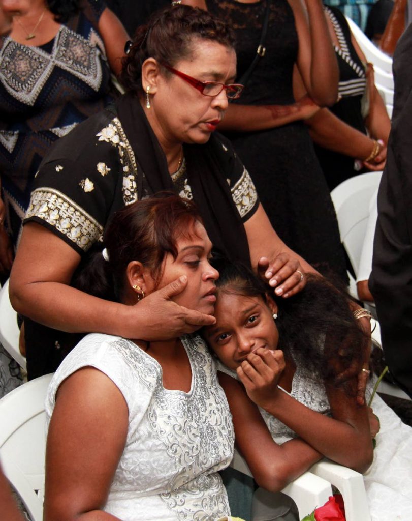 Shanta Sookdeo and her daughter Shelene, mother and sister of Sunil Sookdeo, are comforted by a relative during his funeral at their Gandhi Village, Debe home yesterday. 
PHOTO BY ANIL RAMPERSAD.