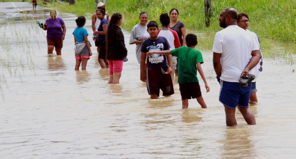Residents of Siew Trace, Debe, walk through flood waters after being forced to leave their homes.