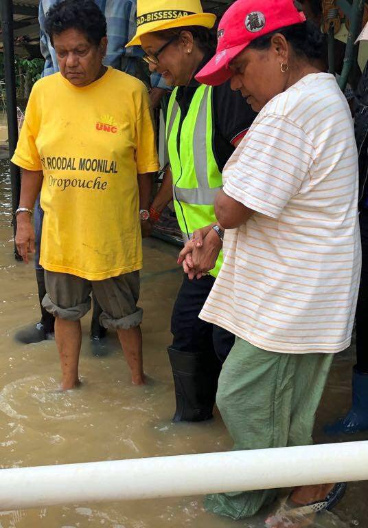 OUT ON TOUR: Opposition Leader Kamla Persad-Bissessar, centre, is helped as she walks through flood waters in Siparia yesterday.