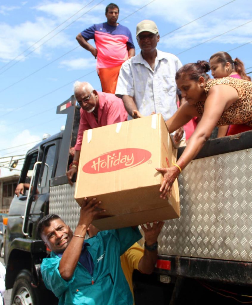 Chairman of the Siparia Regional Corporation Glenn Ramadharsingh strains under the weight of a box of relief supplies in Woodland on the weekend.