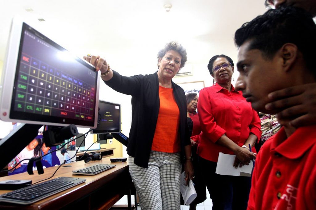 LIFE CHANGING: President of the Children’s Ark, Simone de la Bastide and director Kathy Ann Waterman look on as Khaleel Mohommed demonstrates how to use the Advanced Eyegaze Technology device last week at the National Centre for Persons with Disabilities in San Fernando.