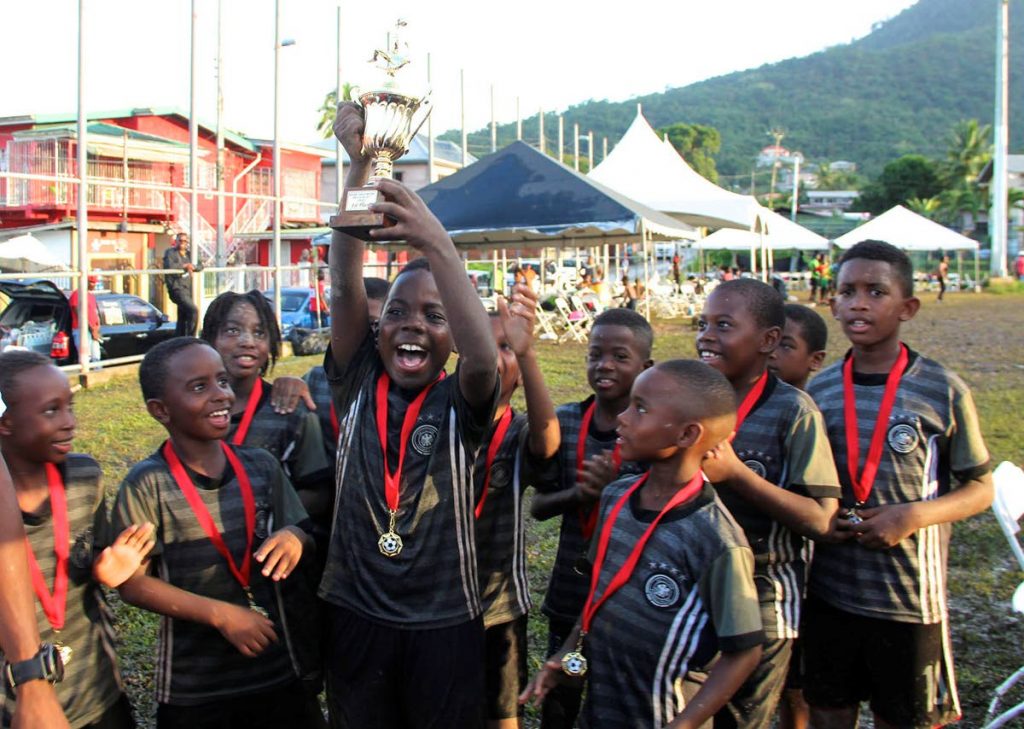 Masons Elite Under-9 players lift the age group trophy at the Trendsetter Hawks Football Tournament last weekend at the Brian Lara Recreation Ground, Santa Cruz.