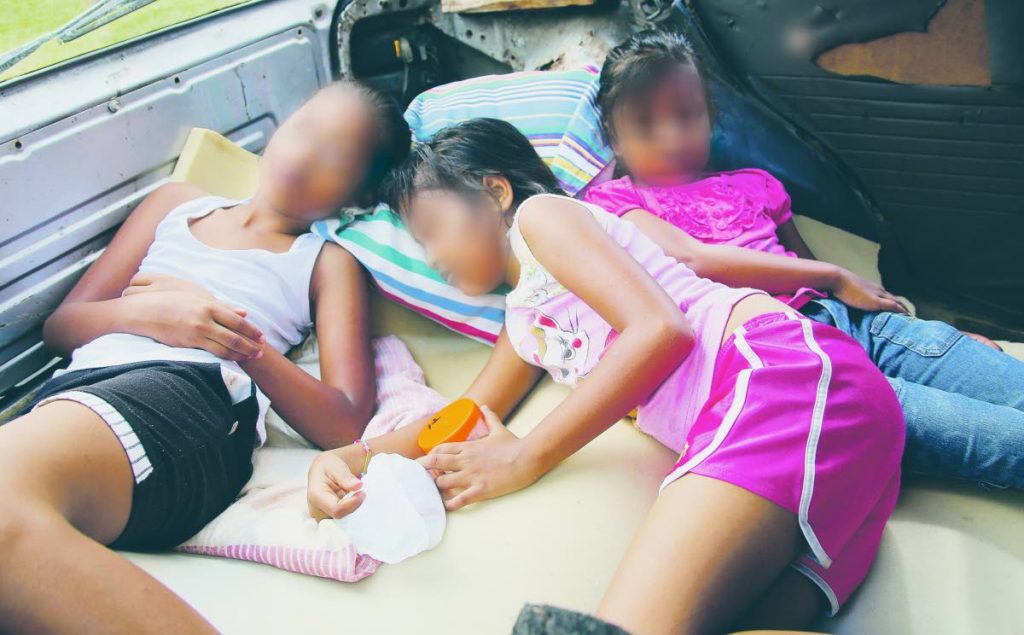 CROUCH UP: Three sisters pretend to sleep to show how they crouch together at nights with their parents in a car in which they live after the family was 
evicted from their home in south Oropouche. PHOTO BY VASHTI SINGH