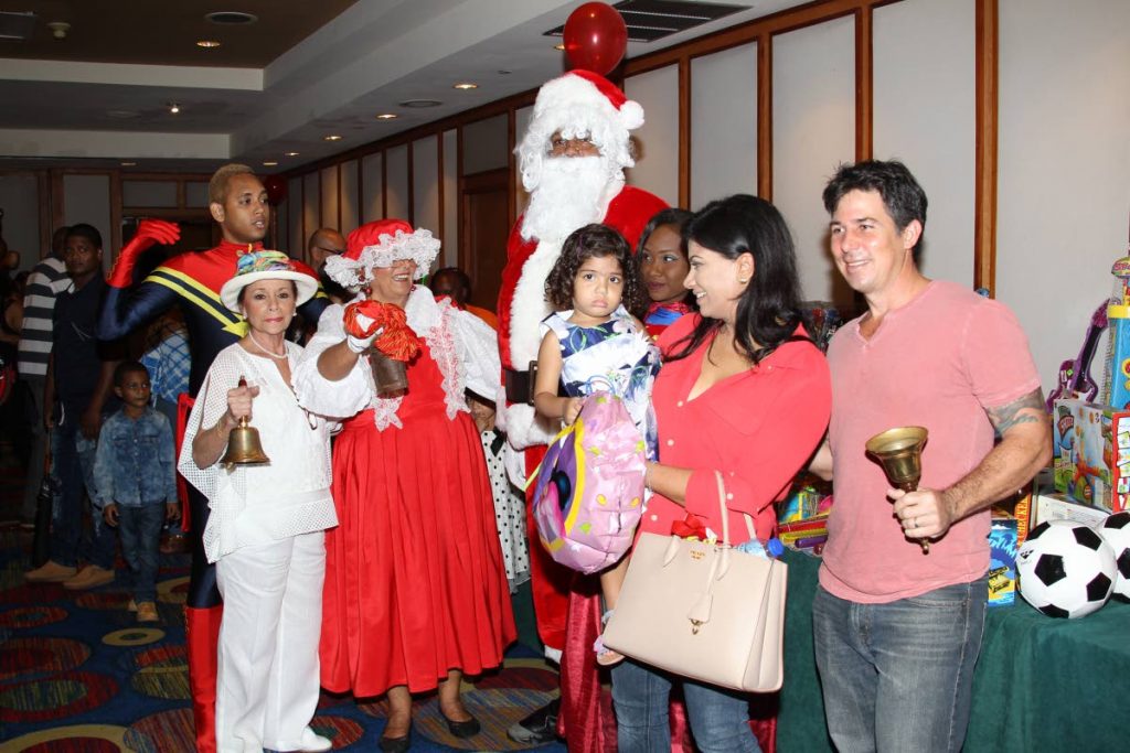 MAKING MERRY: Hannah Janoura (left) rings in the Christmas season at her annual bazaar at the Trinidad Hilton yesterday.  Accompanying her are Santa Claus, Mrs Claus and television personality Shelly Dass-Clarke, her husband Robert Clarke and their daughter Ava.  PHOTO BY RATTAN JADOO