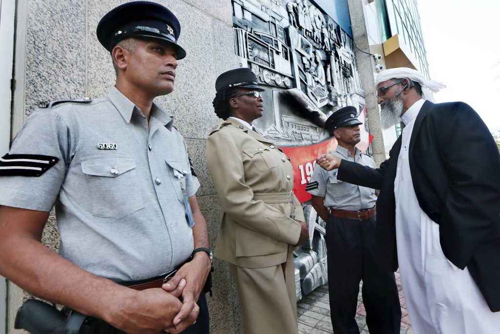 Back in February: In this February 3 file photo head of the Islamic Front Umar Abdullah, right, chats with police outside Parliament, Port of Spain. Abdullah yesterday claimed police targeted Muslims in exercises in Mayaro.