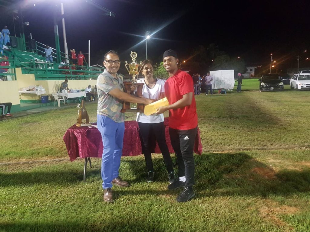 Winners’ Nicholas Pooran, right, collects the league trophy from sponsor Vasant Bharath, left, as Bamboo Cricket League PRO Flora Maharaj, centre, looks on.