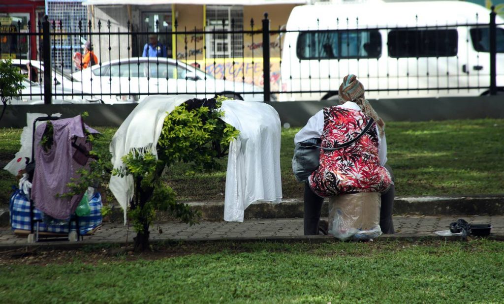 HOME:  A homeless woman dries her clothing on a tree at Tamarind Square, Port of Spain yesterday.