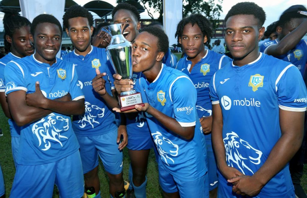 A member of Presentation San Fernando football team kisses the SSFL Premier Division trophy while some of his teammates share their joy after yesterday’s success.
