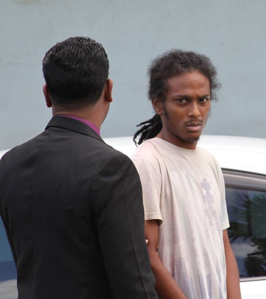 OFF TO COURT: Sheldon Mc Intosh, 23, is escorted to the Chaguanas Magistrates Court yesterday charged with raping a woman he met on Facebook.  PHOTO BY LINCOLN HOLDER