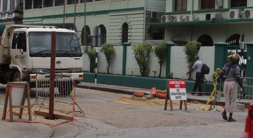 PARTIAL CLOSURE: Pedestrians walk along Knox St, PoS yesterday as a sign indicates works being carried out. Construction works extended beyond the northern perimeter at the origin site of the Parliament Building, as public access on Knox Street, has been blocked to motor vehicular traffic with a some limitations to pedestrians on both sides, as repairs to the Red House continue. PHOTO BY ROGER JACOB