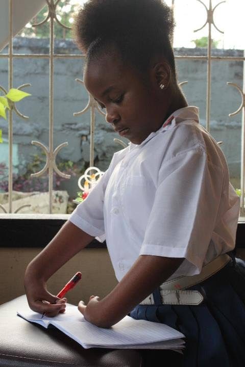  I am a writer: Danika Linton, 11, who can't bend her arms, writes at her home in St James after classes at Sacred Heart Girls RC School. 
She is in Standard Three. Photo by Steffon Douglas