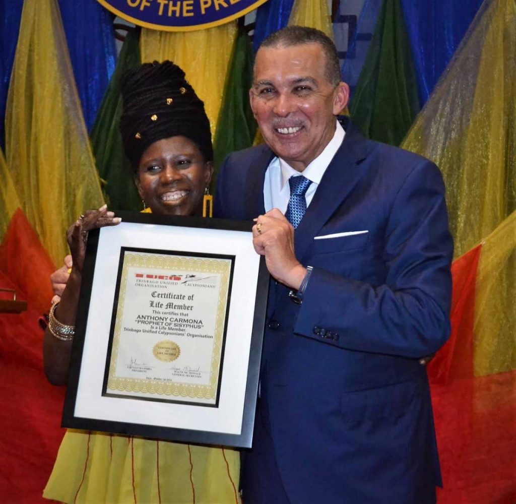 President Anthony Carmona receives the Certificate of Life Membership from Twiggy.