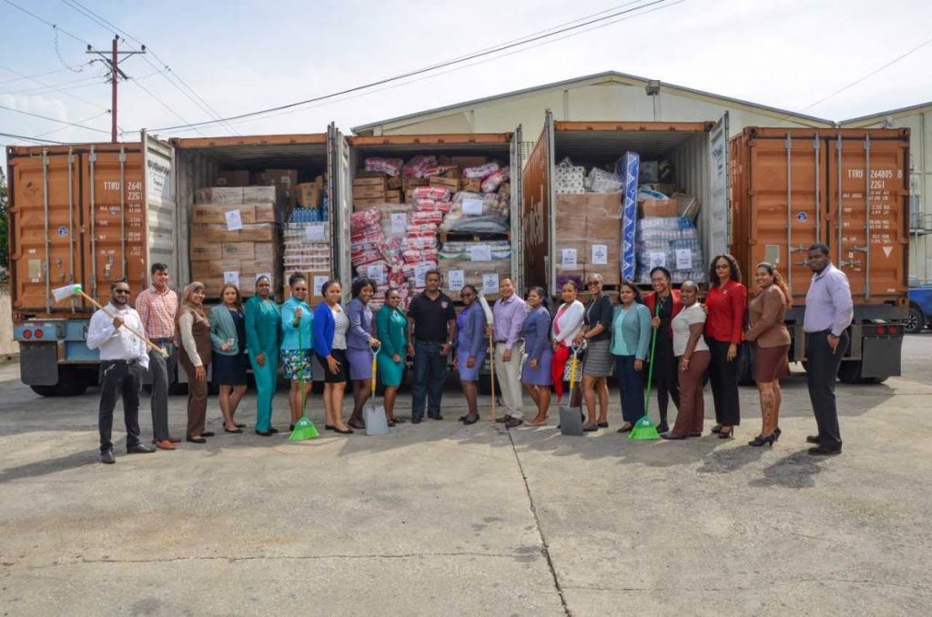 HELPING HAND: Members of the ANSA McAL Hurricane relief group pose next to steel containers filled with relief items destined for hurricane-ravaged Dominica.