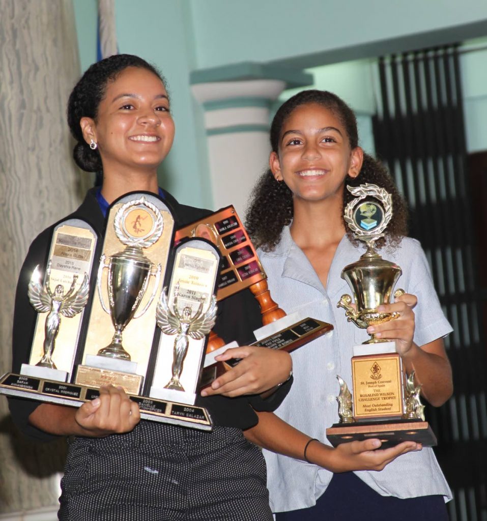 St Joseph’s Convent Port of Spain’s Leigha Clarke, left, had to get help from her younger sister Giana, also a student of the school, is holding all of her trophies awarded to Leigha during an awards ceremony at the school on Thursday.