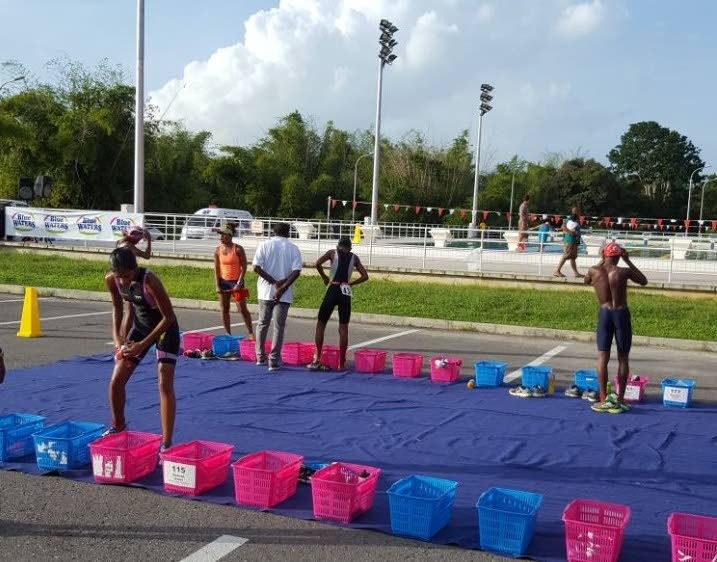 Athletes change to transition from the run to the pool during the TTTF School Series Aquathlon, yesterday, at the National Aquatic Centre, Couva.