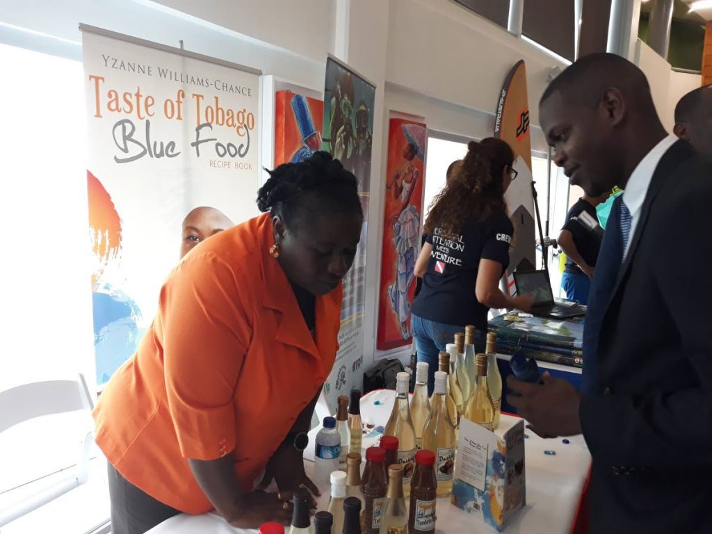 Travis Robinson, 22, Parliamentary Secretary in the Ministry of Tourism and Aviation in the Bahamas, samples dasheen wine made by entrepreneur Yzanne Williams-Chance, left, at the career fair held as part of the Youth Tourism symposium on Monday hosted by the Division of Tourism at the Shaw Park Cultural Complex.