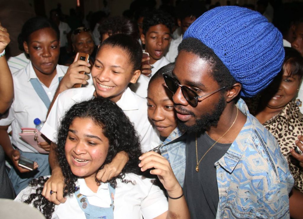 WE LOVE YOU: Reggae artiste Jamar ‘Chronixx’ McNaughten yesterday with ecstatic St Joseph Convent students at City Hall in San Fernando.