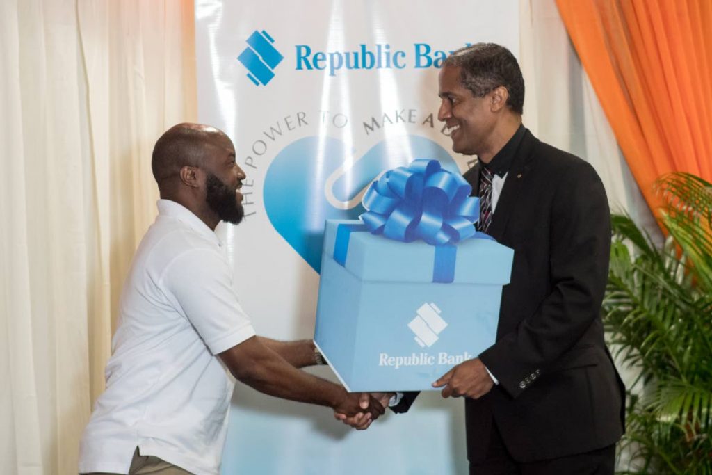 Kevon Gervais from the National Carnival Commission (left) accepts his token from Republic Bank’s Managing Director Nigel Baptiste at the launch of the 2017-2018 edition of the Power To Make A Difference programme.