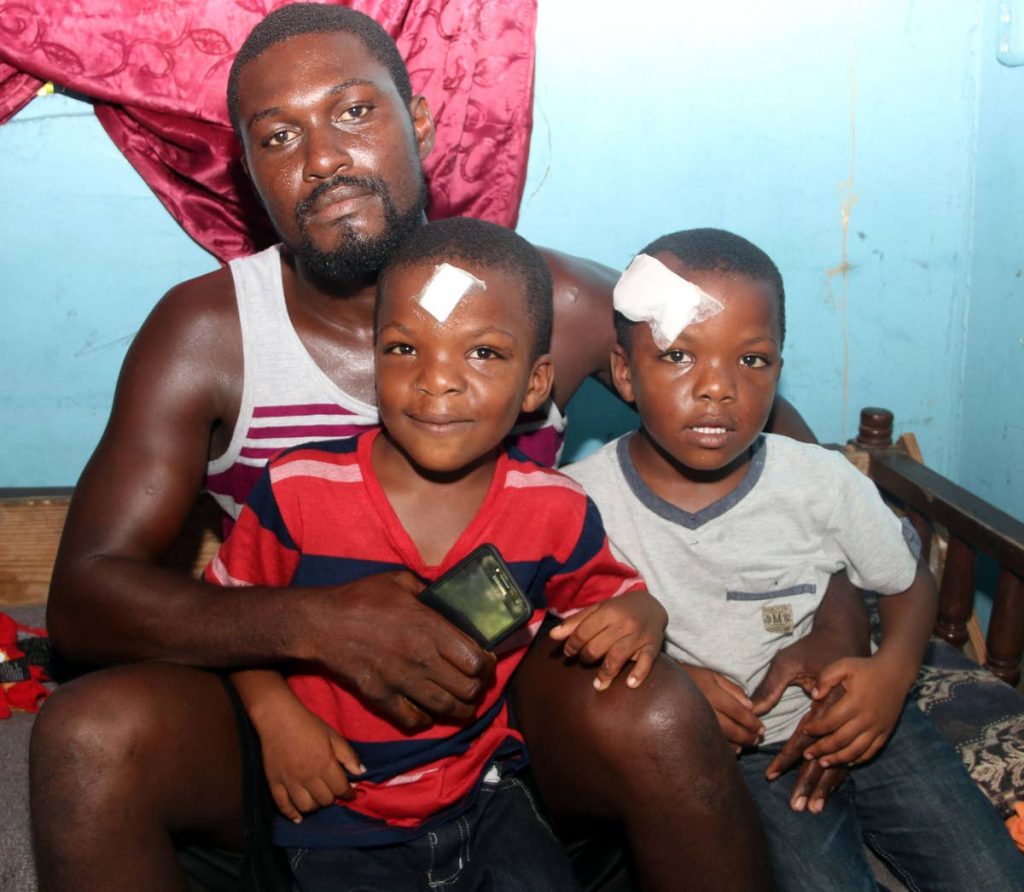 Head injuries: Kelvin George at his home in Siparia with and his twin sons Ishmaaeel, left, and Ishmael who are recovering from head injuries. George believes they were slashed with a broken bottle by a bully at Siparia RC School. Photo by Ansel Jebodh